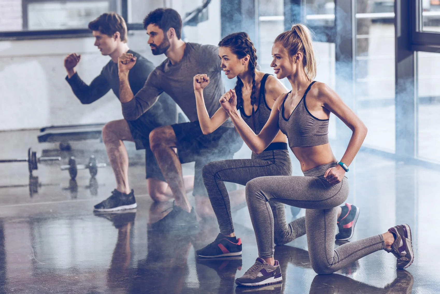 Gruppe sportlicher junger Menschen in Sportbekleidung, die im Fitnessstudio Ausfallschrittübungen machen, Aerobic-Fitnesskonzept